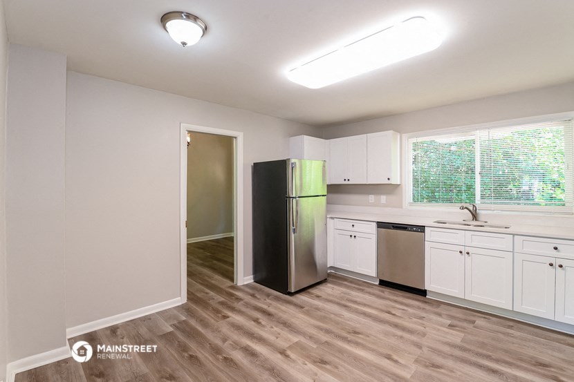 the kitchen of an apartment with white cabinets and a stainless steel refrigerator