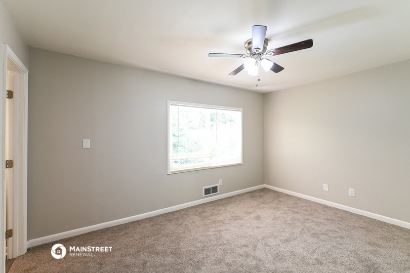 an empty room with a ceiling fan and a window