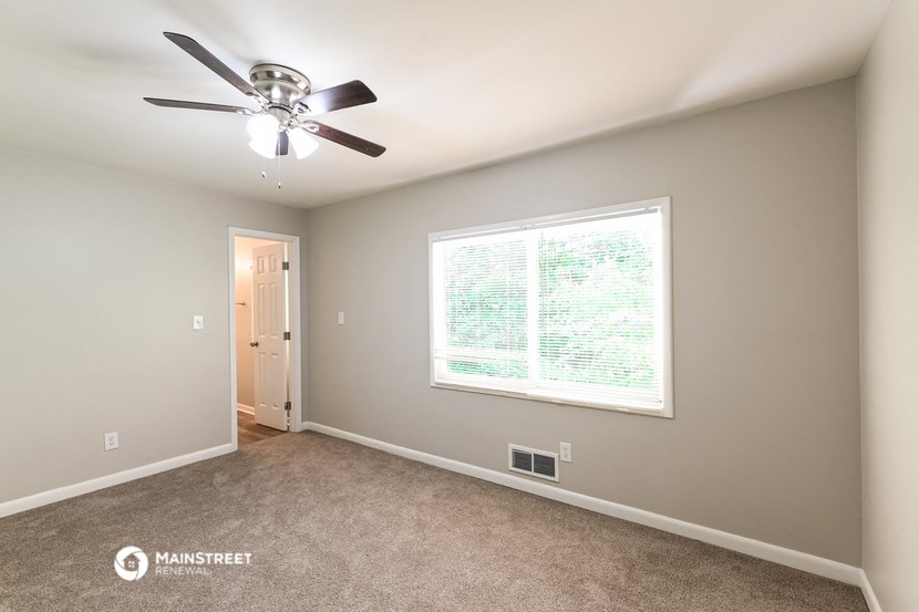 the master bedroom has a ceiling fan and a large window