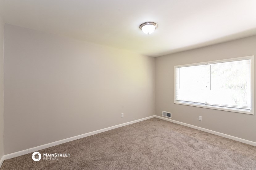 the spacious bedroom with carpet and a large window