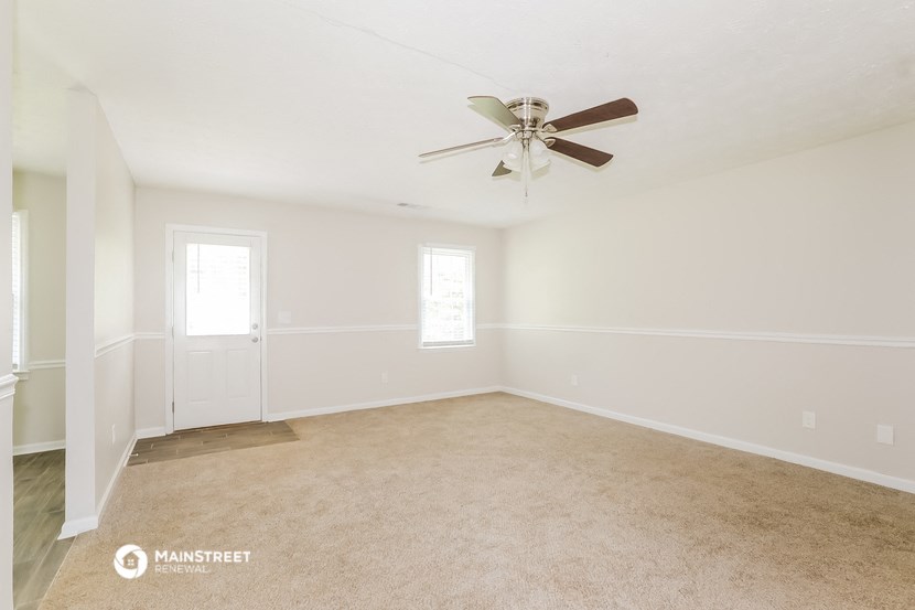 the spacious living room with ceiling fan and carpet