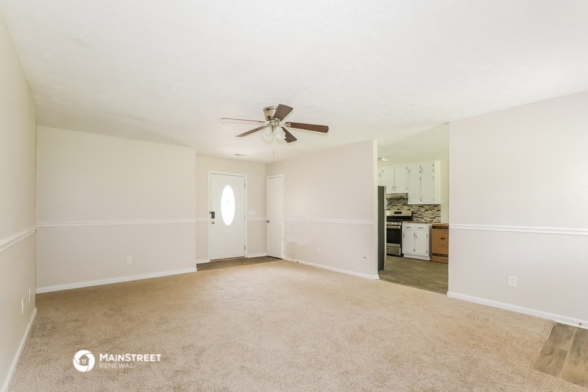 an empty living room with a ceiling fan and white walls