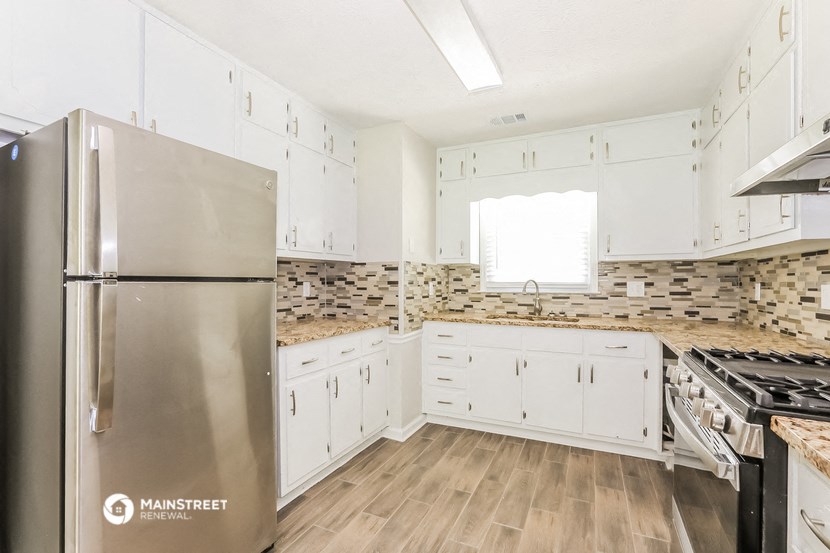 a kitchen with white cabinets and a stainless steel refrigerator