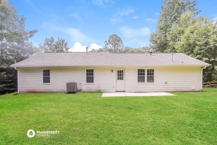 the front of a white house with a green lawn and trees