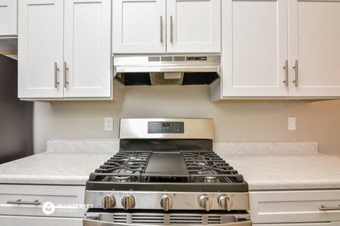 a kitchen with white cabinets and a stove top oven