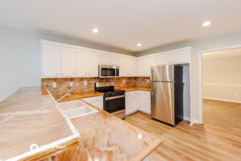 a kitchen with white cabinets and a stainless steel refrigerator
