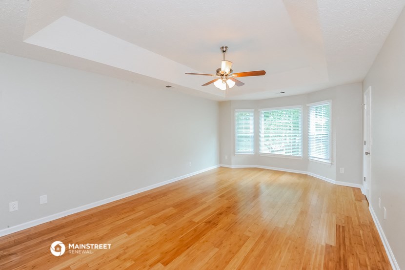 the living room and dining room with wood floors and a ceiling fan