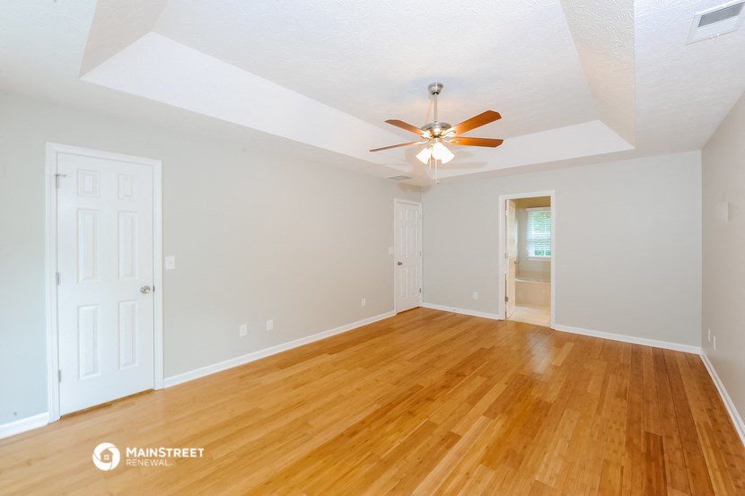 the living room and dining room with hardwood floors and a ceiling fan