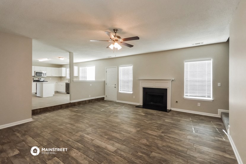 an empty living room with a ceiling fan and a fireplace