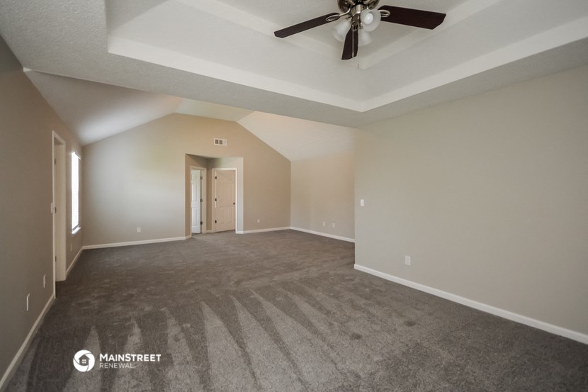 an empty living room with a ceiling fan