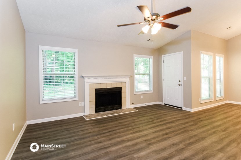 an empty living room with a fireplace and a ceiling fan