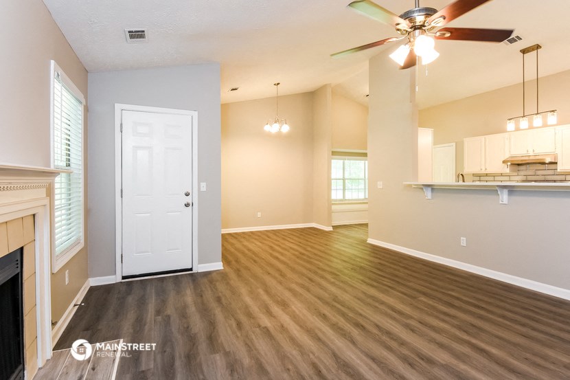 an empty living room with a fireplace and a ceiling fan