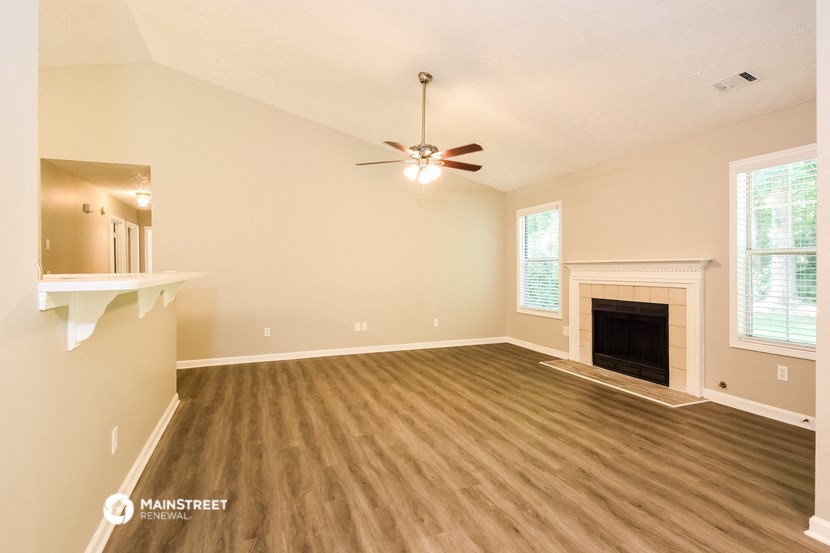 the spacious living room with fireplace and ceiling fan