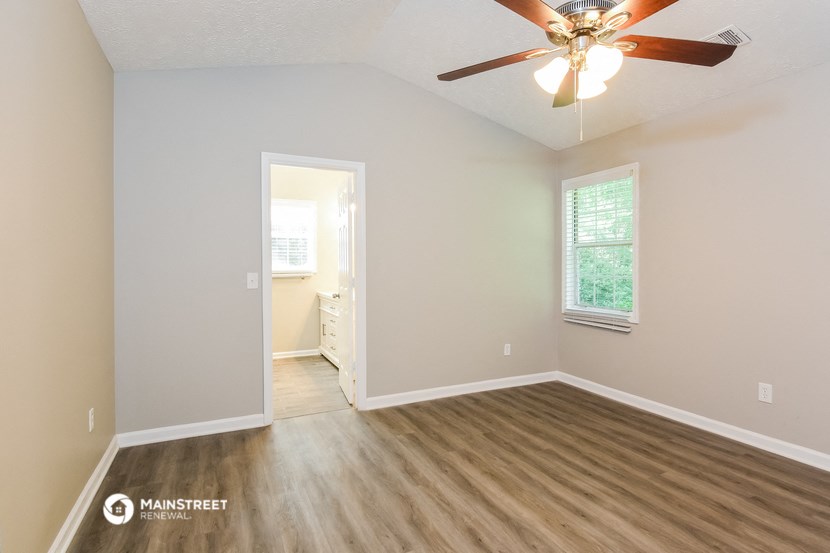 the spacious living room with hardwood flooring and a ceiling fan