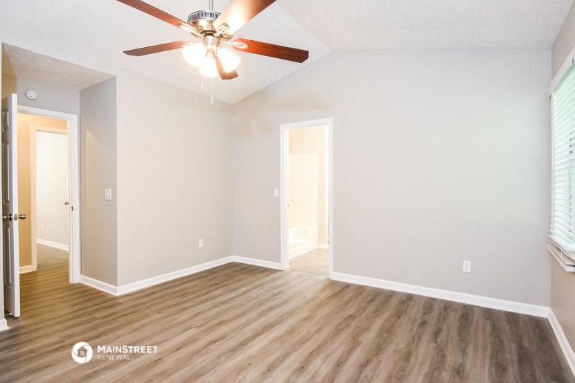 the spacious living room with hardwood floors and a ceiling fan