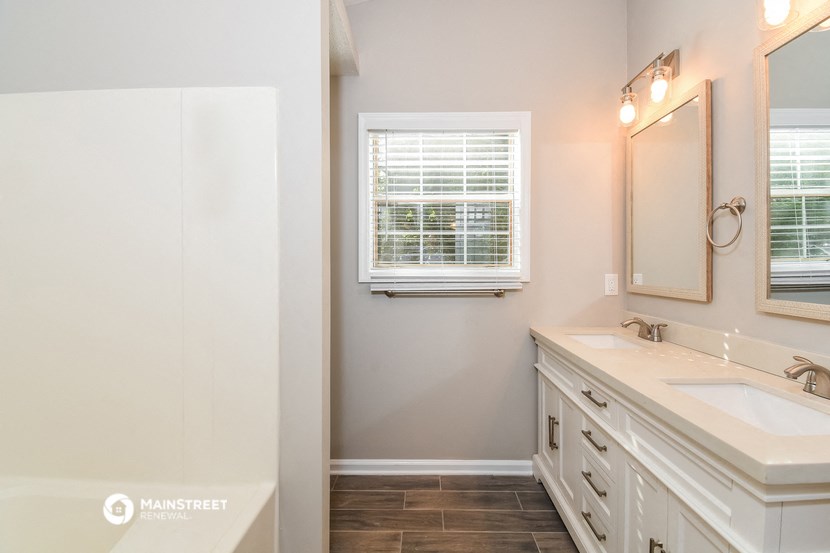 a white bathroom with two sinks and a window
