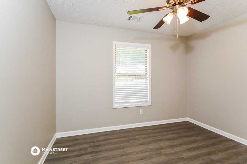 an empty room with a ceiling fan and a window
