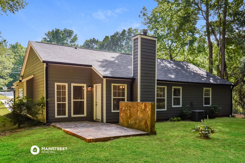 a small house in the woods with a yard and a porch