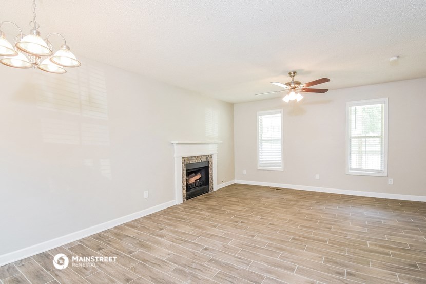 the living room with a fireplace and a ceiling fan
