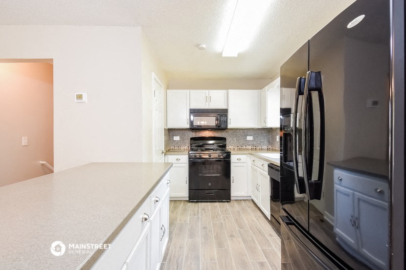 a large kitchen with white cabinets and black appliances