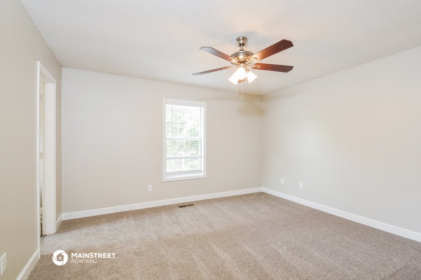 the spacious living room with ceiling fan and carpet