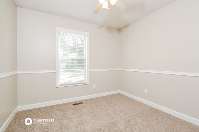 the spacious bedroom with carpeted flooring and a window