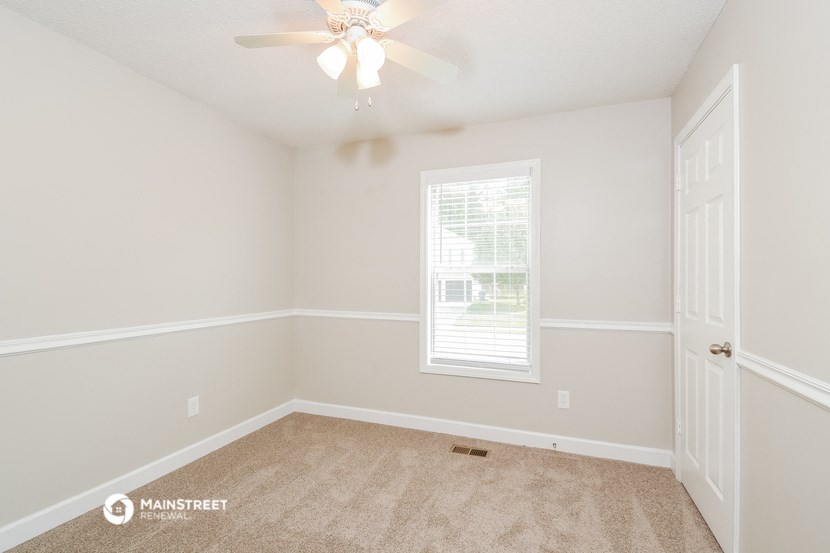 the spacious bedroom with carpeted flooring and a ceiling fan