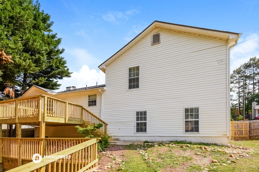 a view of the back of a house with a wooden deck