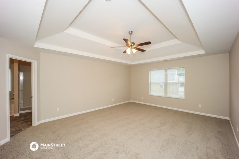 the spacious living room with ceiling fan and carpet