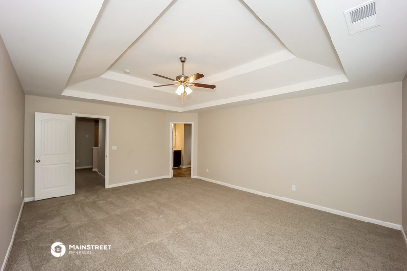 the spacious living room with ceiling fan and carpeting