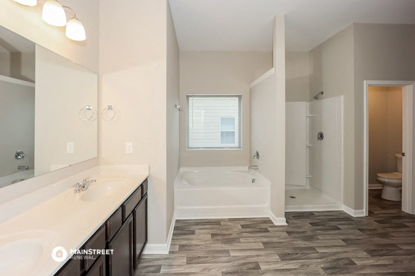 the master bathroom of a new home with a tub and a sink and a mirror