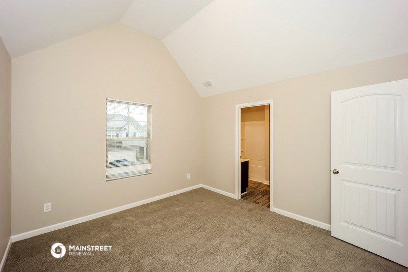 a bedroom with carpet and a door to a closet