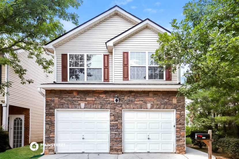 a white and brick house with two garage doors