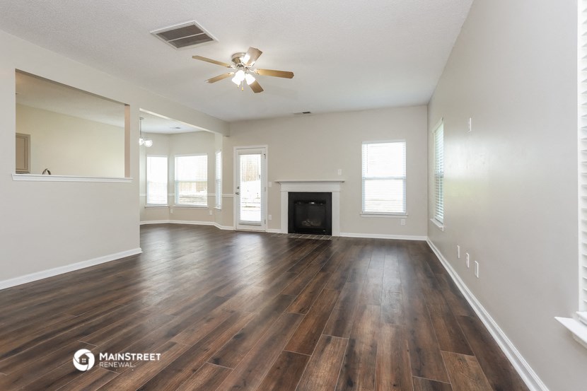 an empty living room with wood flooring and a ceiling fan
