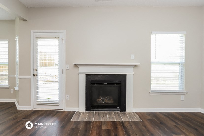 the living room with wood floors and a fireplace