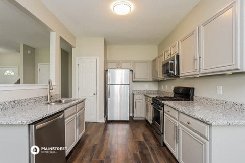 a kitchen with white cabinets and granite counter tops and a stainless steel refrigerator