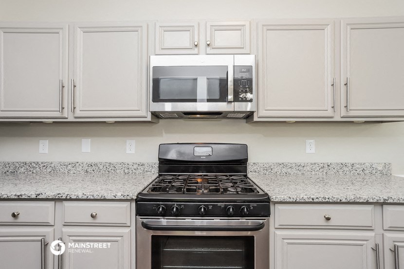 a kitchen with white cabinets and a stove and a microwave