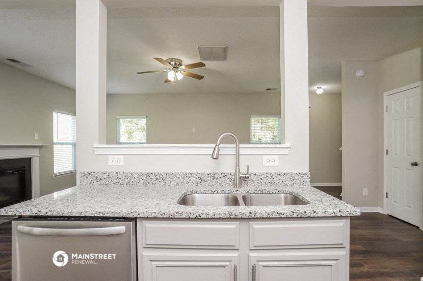 an empty kitchen with a sink and a ceiling fan