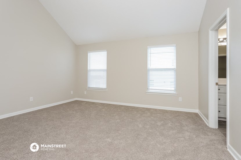 a bedroom with carpet and two windows and a closet