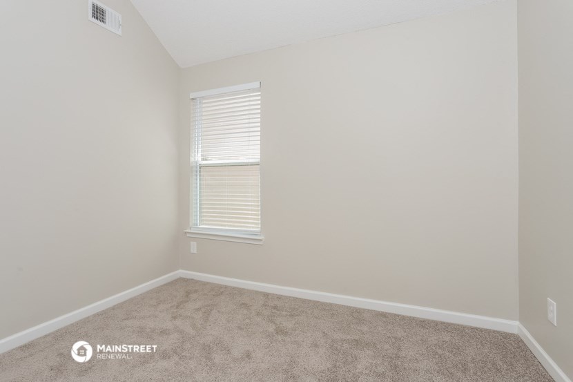 a bedroom with a carpeted floor and a window