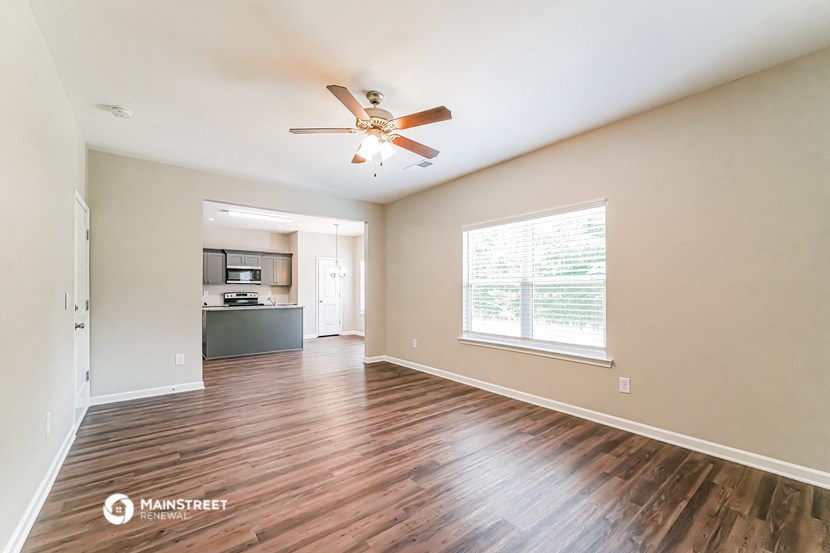 an empty living room with a ceiling fan and a window