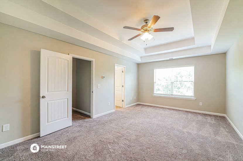an empty living room with a ceiling fan and a window