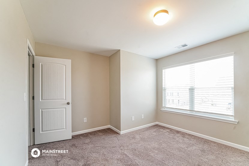 an empty room with a window and a white door