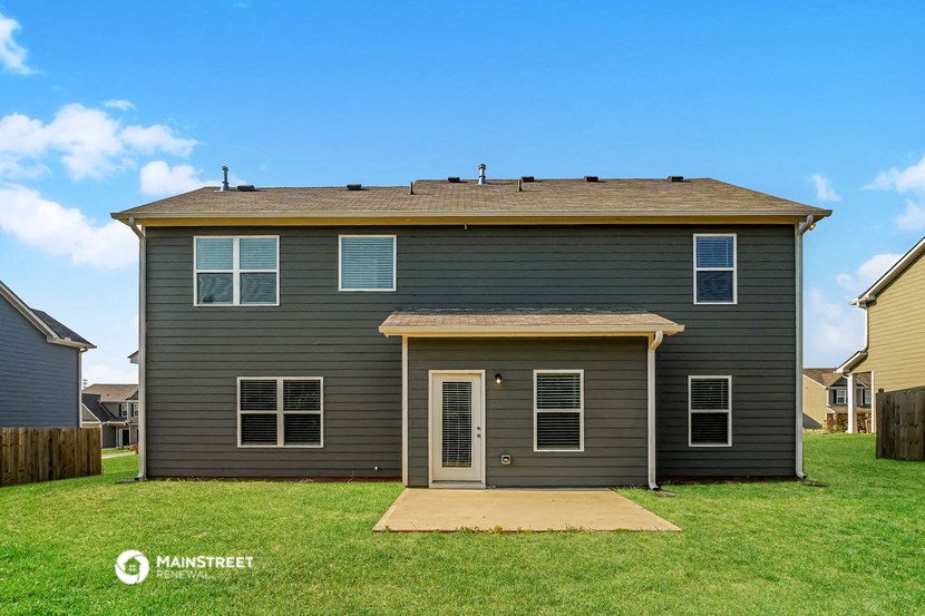 a gray house with a lawn and a blue sky