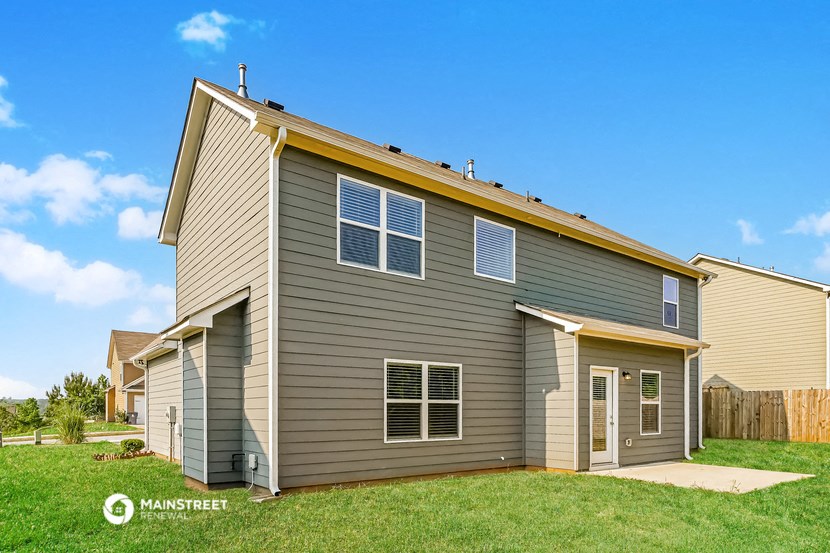 a gray house with a yellow roof on a green lawn