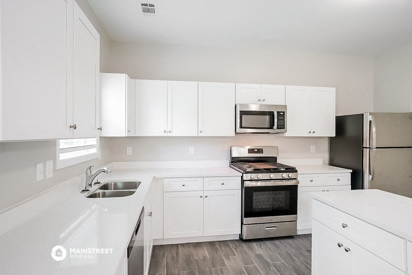 a white kitchen with white cabinets and stainless steel appliances