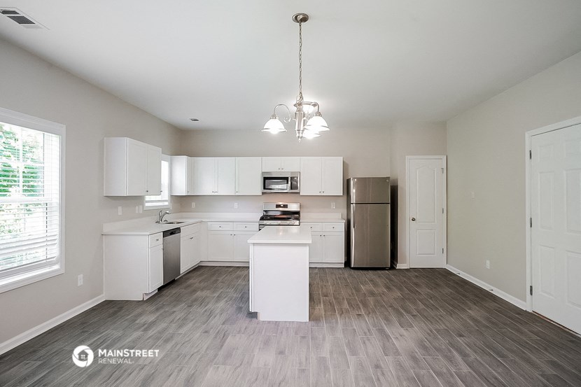the spacious kitchen with white cabinets and stainless steel appliances