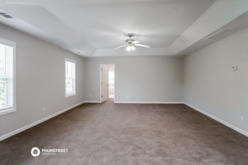 the spacious living room with carpet and ceiling fan