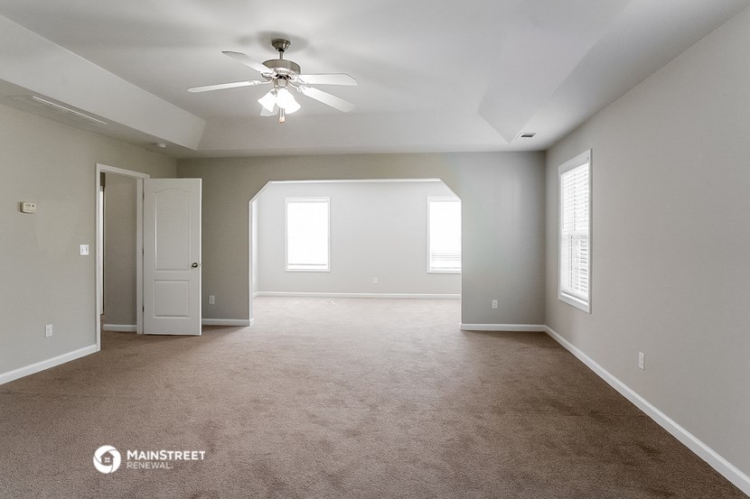 the spacious living room with carpet and a ceiling fan