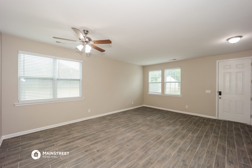 an empty living room with a ceiling fan and a white door